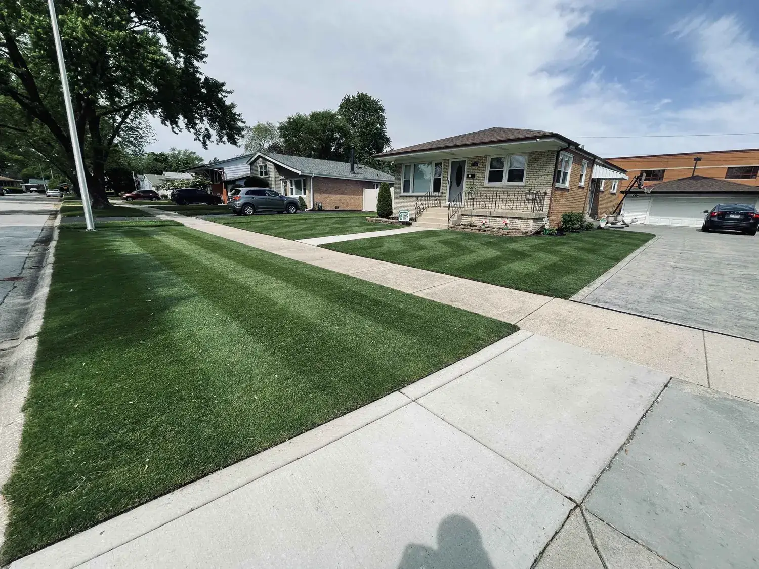 A residential lawn maintained by A.R Lawn Service, with mowing stripes and neatly trimmed edges