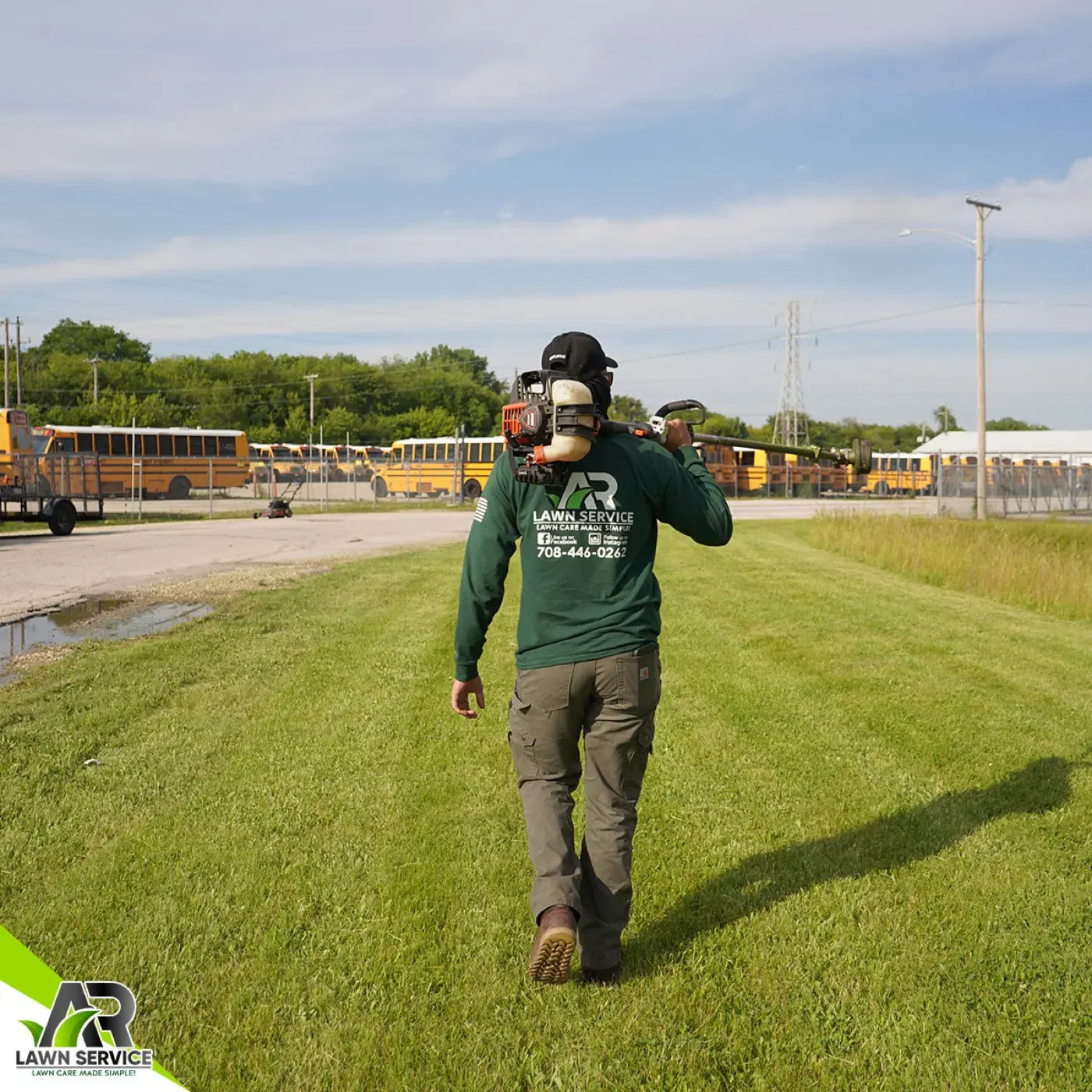 An A.R Lawn Service crew member with trimming equipment on a property visit